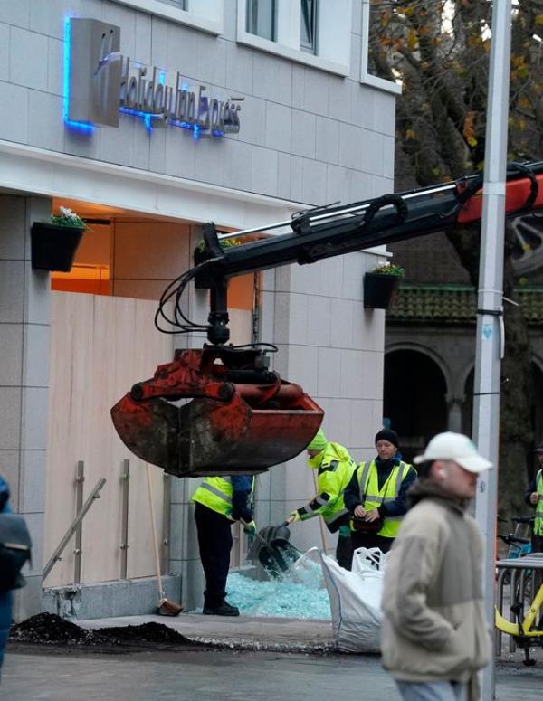 Workers clean up the debris from broken windows of the Holiday Inn Express. Photo: Brian Lawless/PA Wire Photo: Brian Lawless/PA Wire