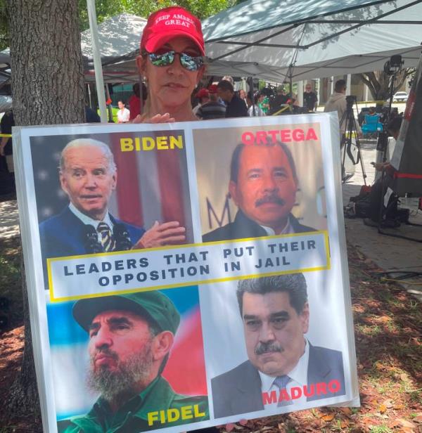 Madelin Munilla, 67, who came to Miami as a child when her parents fled Fidel Castro's Cuba, holds up a sign comparing President Joe Biden to Castro and other Latin American leaders at a rally outside the Wilkie D. Ferguson Jr. U.S. Courthouse, on June 13, 2023, in Miami. 