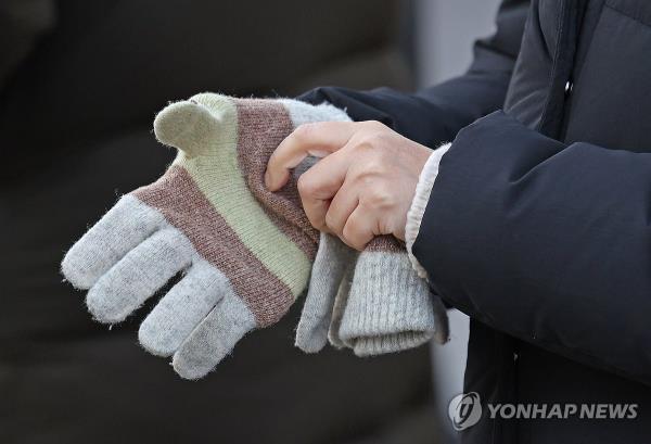 A pedestrian puts on gloves near Gwanghwamun Square in Seoul on Dec. 21, 2023, as the apparent temperature dropped to minus 22 C. (Yonhap)