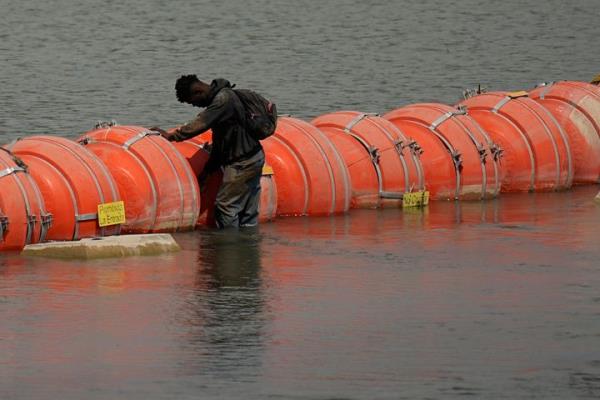 A migrant from Colombia stands at a floating buoy barrier as he looks to cross the Rio Grande from Mexico into the U.S. on Aug. 21 in Eagle Pass, Texas.