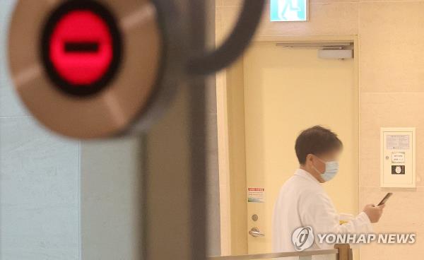 A medical worker walks while looking at his smartphone at a hospital in Seoul on March 29, 2024. (Yonhap)