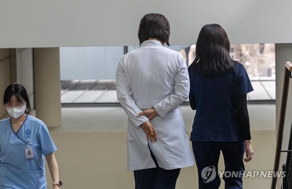 Doctors walk down a flight of stairs at a hospital in Seoul on March 25, 2024. (Yonhap)