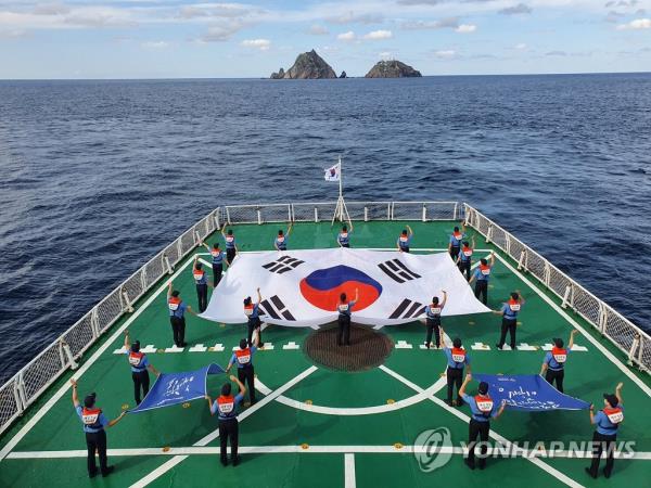 The crew of a Korea Coast Guard ship unfurls banners carrying the phrase 