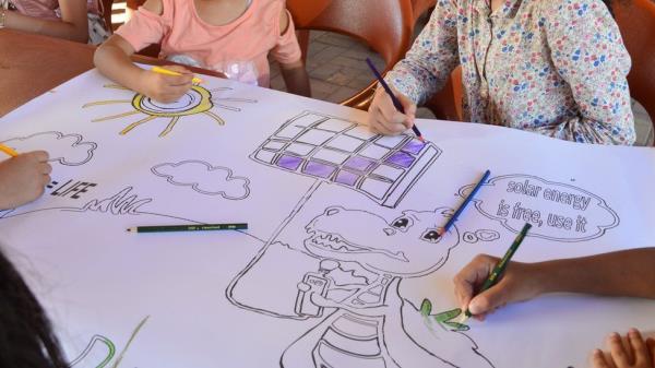 Children paint a poster encouraging the use of solar energy.
