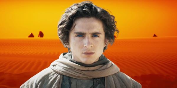 Timothe?e Chalamet as Paul Atreides standing in front of an orange desert background with figures emerging from behind the dunes in Dune: Part Two.